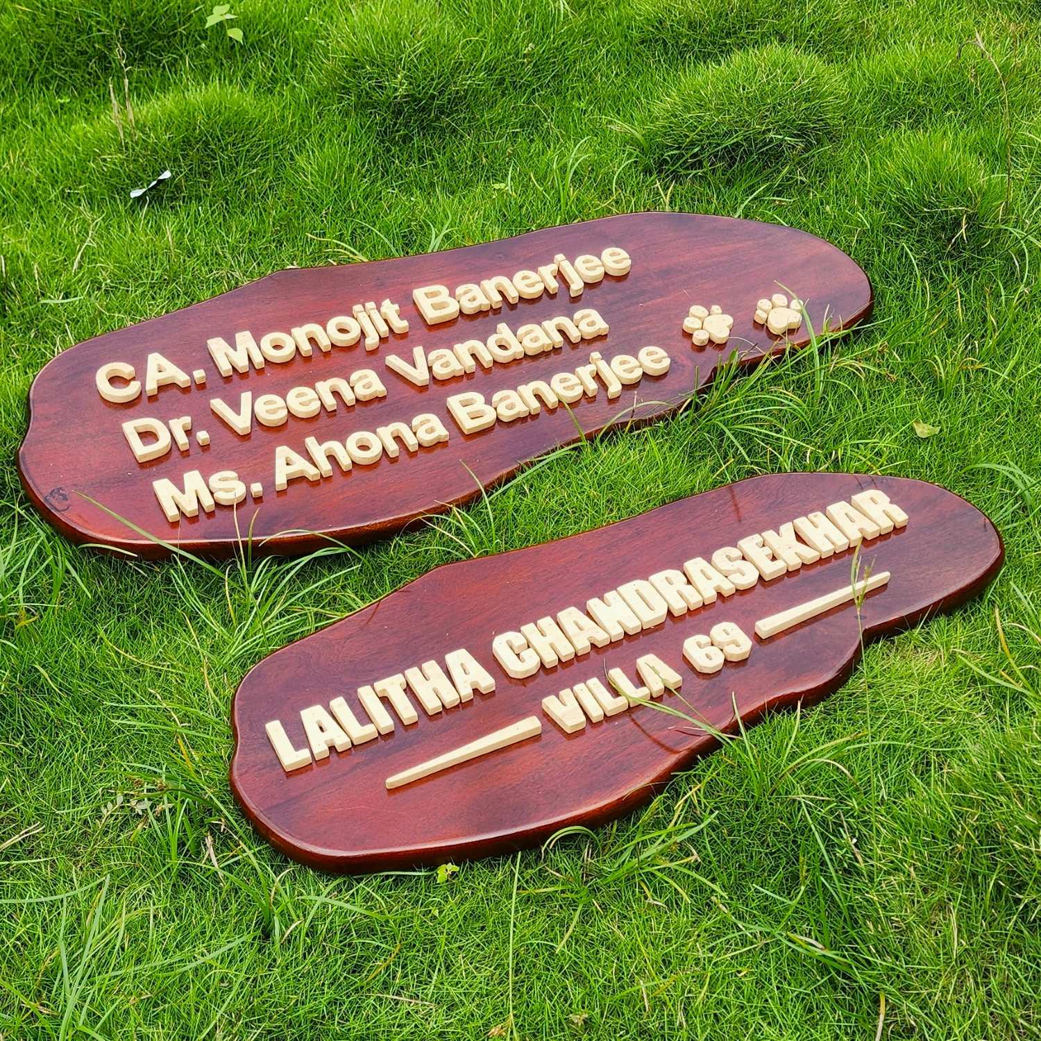 A custom wooden nameplate with raised 3d wood gold lettering reading 'CA. Monojit Banerjee, Dr. Veena Vandana' and pug marks for a pet 