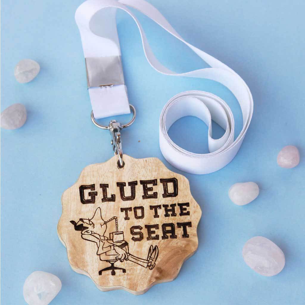 Glued To The Seat Funny Medal. This wooden medal is the best gift for coworkers. This custom medal will make great office gifts. Buy more customised gifts for colleagues from The Woodgeek Store.